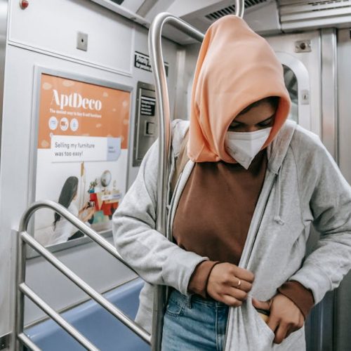 Muslim female in casual clothes medical mask and traditional headscarf in subway train