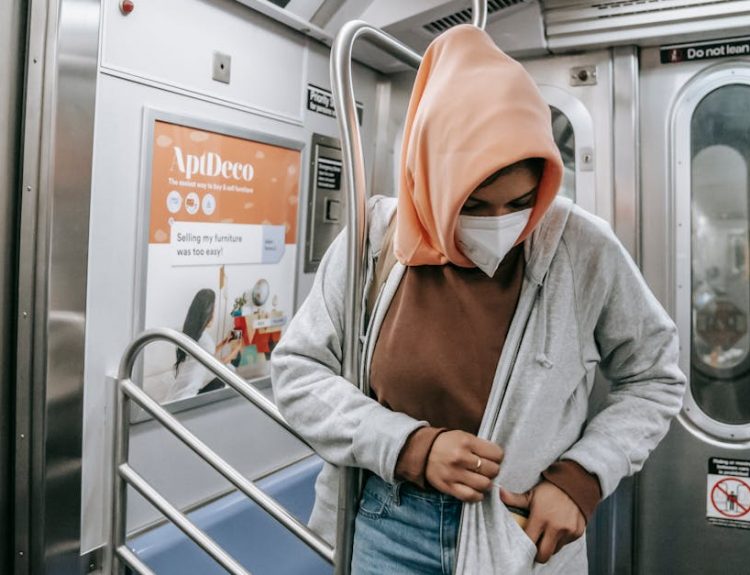 Muslim female in casual clothes medical mask and traditional headscarf in subway train