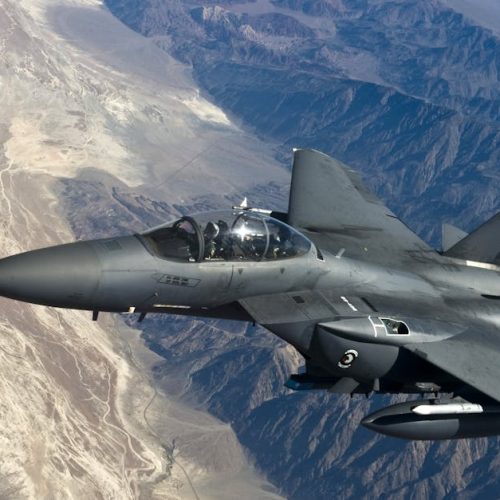 A military fighter jet flying above rugged mountain ranges, showcasing advanced aviation technology.