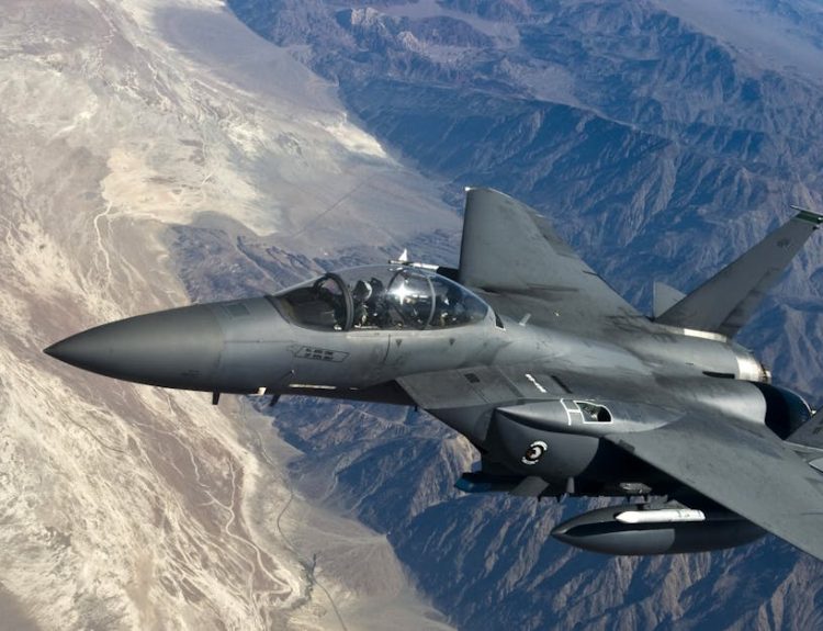 A military fighter jet flying above rugged mountain ranges, showcasing advanced aviation technology.