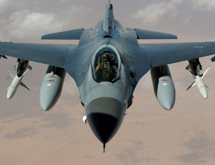 Powerful fighter jet soaring through clouds with visible missiles.