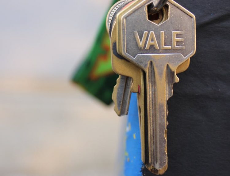 A detailed view of a metallic key with 'Vale' engraved on it, hanging against a blurred background.