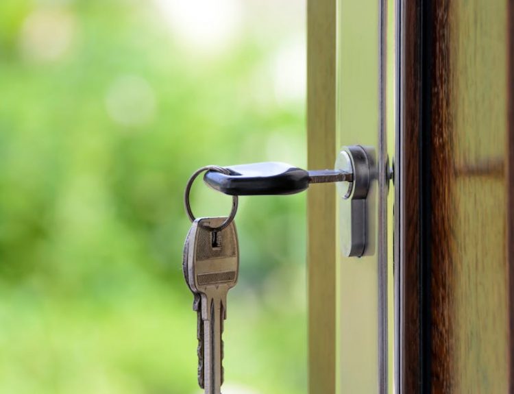 Key inserted in door lock against a blurred green background, symbolizing security and real estate.