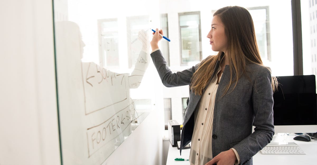 Professional woman writing on a whiteboard in an office environment, focusing on ideas.
