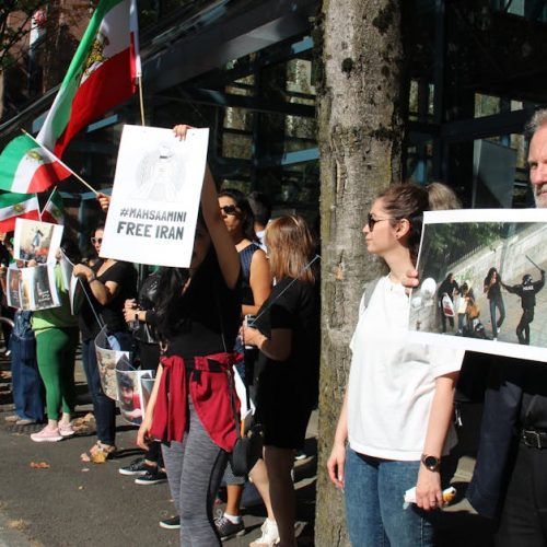 A peaceful protest in Vancouver advocating for Iranian rights with flags and placards.