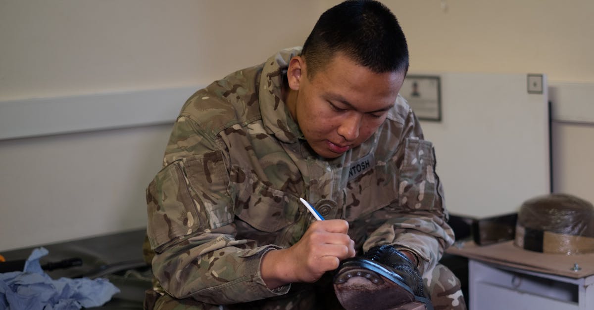 A British soldier is polishing boots indoors, showcasing military routine and discipline.