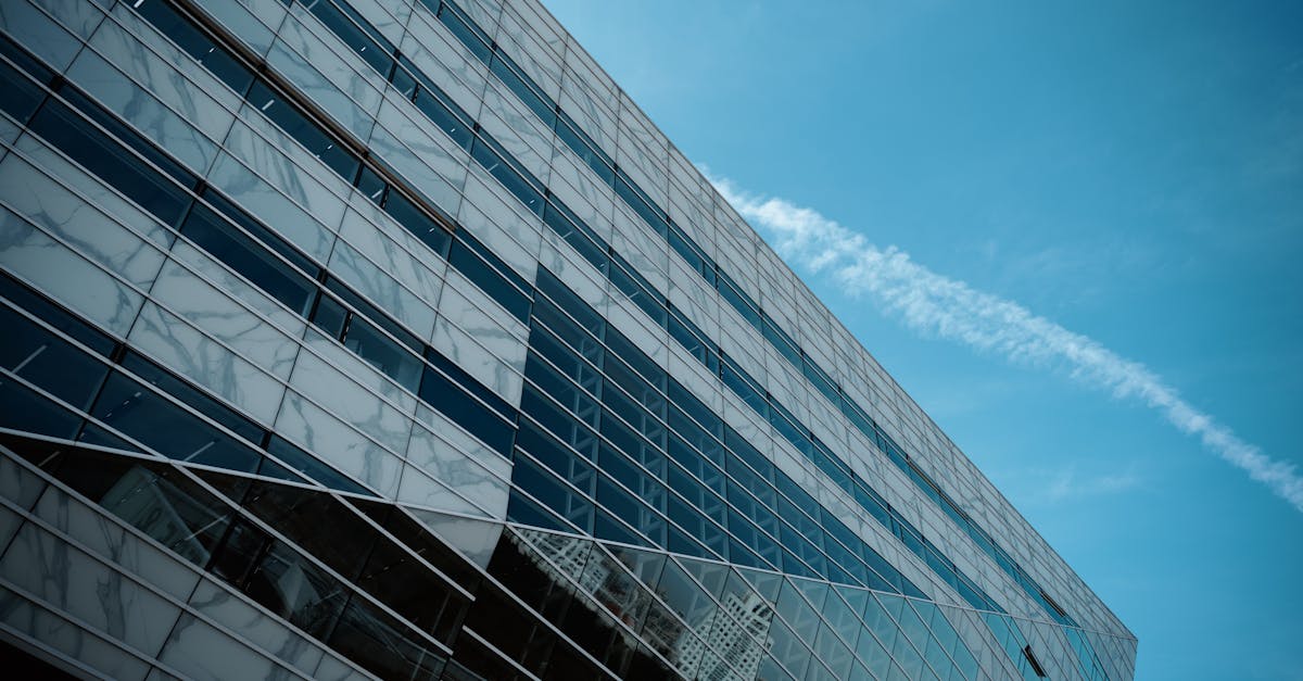 A striking low angle view of a modern glass building against a clear blue sky, emphasizing urban architecture.