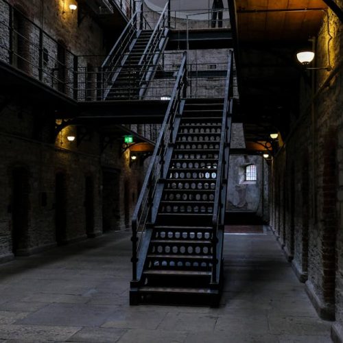 Explore a dimly lit corridor with a historic staircase, atmospheric and intriguing.