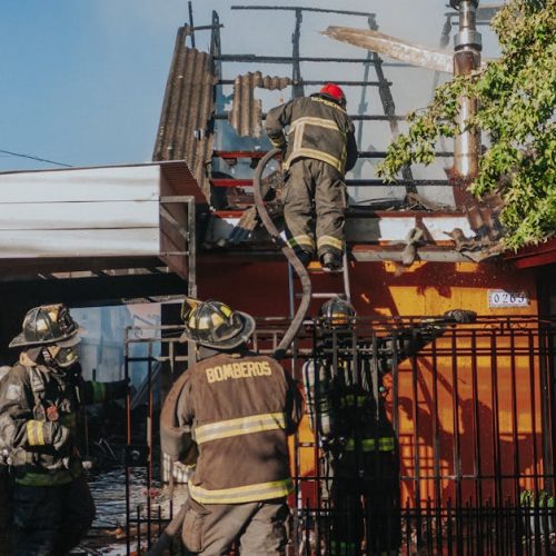 Firefighters working to extinguish a house fire, showcasing bravery and teamwork outdoors.