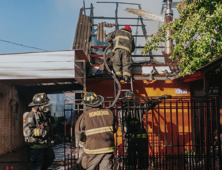 Firefighters working to extinguish a house fire, showcasing bravery and teamwork outdoors.