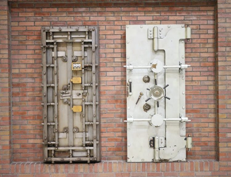 Two steel security vault doors attached to a vintage brick wall, showcasing industrial strength.
