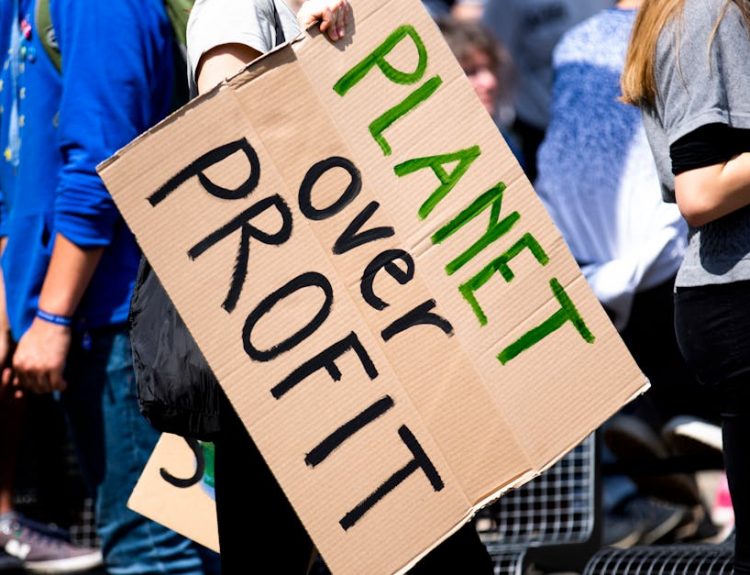 Youth climate protest with participants holding 'Planet Over Profit' sign.