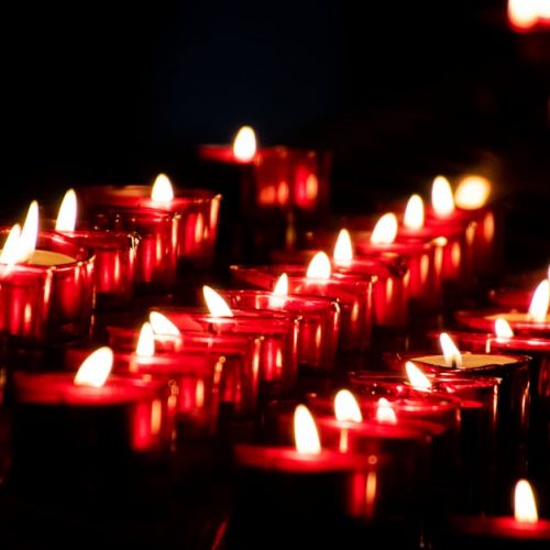 Rows of glowing red candles create a warm, peaceful ambience in the darkness.