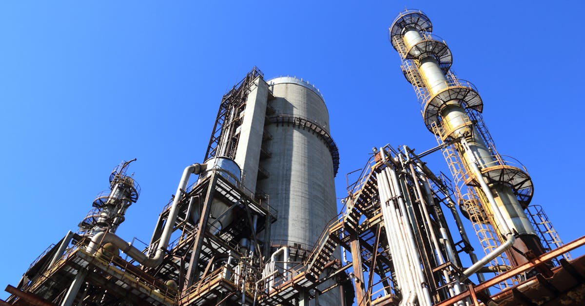 A towering industrial plant under a vivid blue sky, showcasing its intricate architecture and industrial prowess.