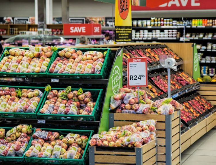 Colorful produce aisle in a supermarket showcasing fresh apples with discount signage.
