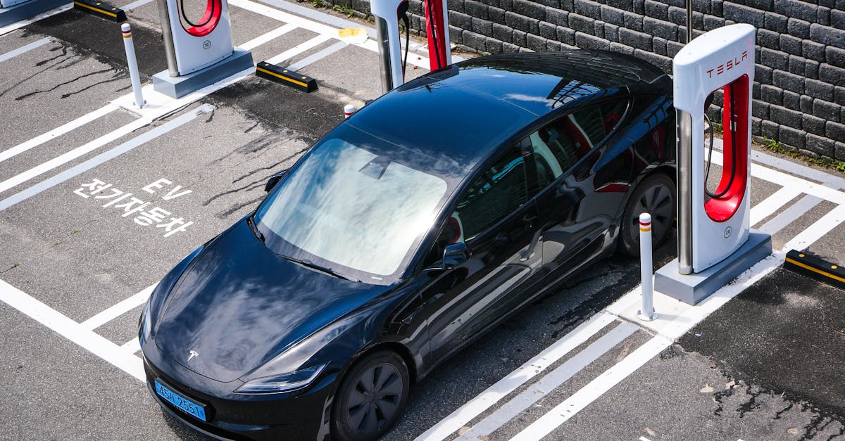 A black Tesla parked at a charging station in an urban setting.