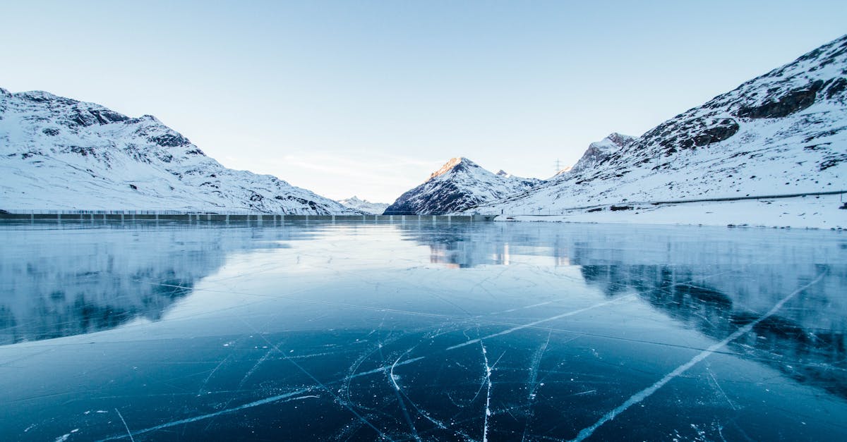 A serene winter landscape featuring a frozen lake surrounded by snow-covered mountains in Switzerland.