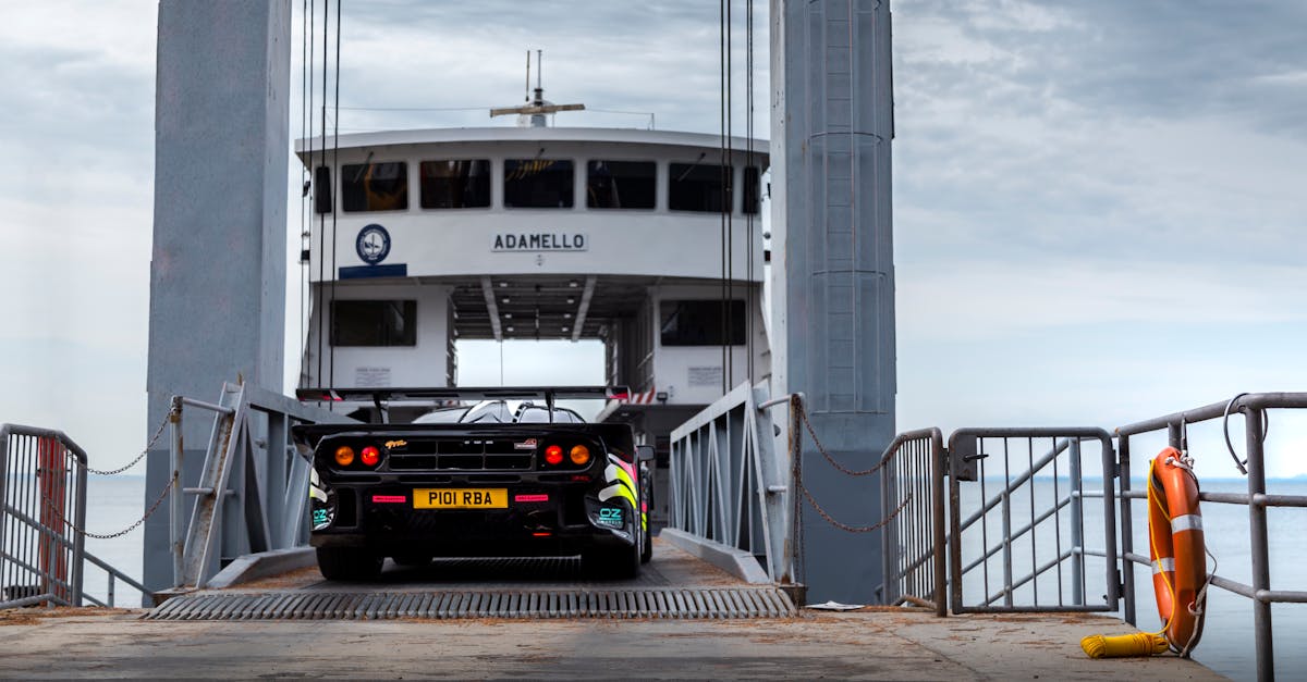 A McLaren supercar driving onto a ferry named Adamello in the scenic Italian Alps.