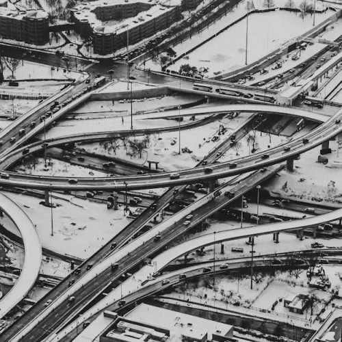 Stunning aerial view of a city highway interchange covered in snow, captured in black and white.