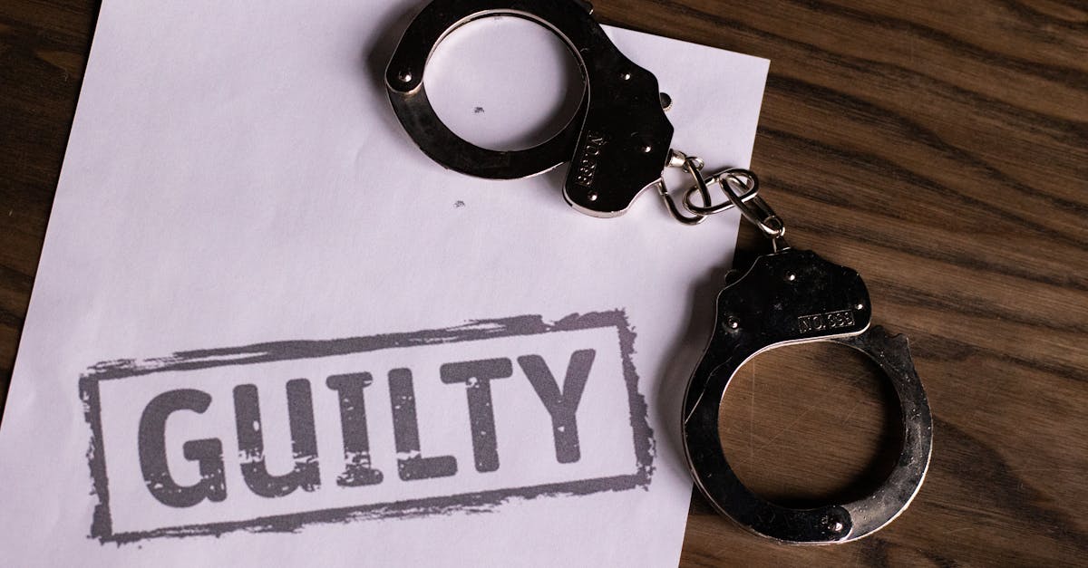 Top view of handcuffs on paper with 'GUILTY' text, symbolizing a verdict or crime.