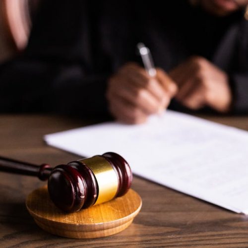 Judge signing documents at desk with focus on gavel, representing law and justice.