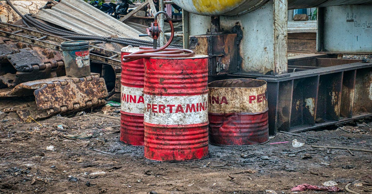 Rusted Pertamina oil barrels in an industrial waste area outdoors in Jakarta, Indonesia.