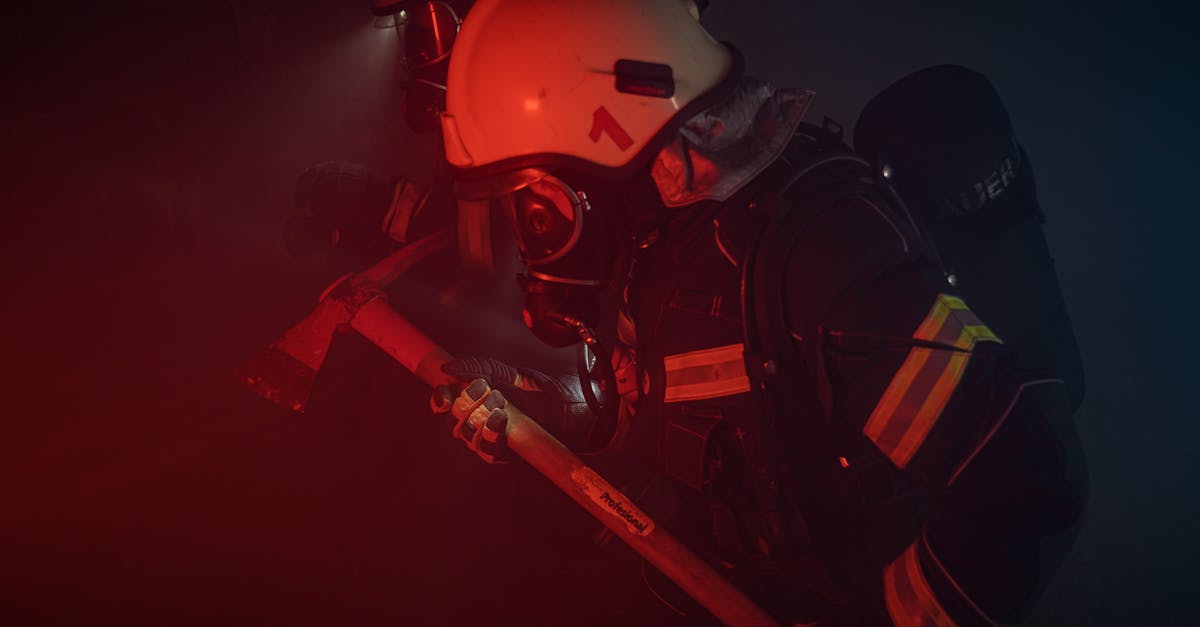 Firefighters in full gear with helmets and axes tackle a smoky emergency situation.