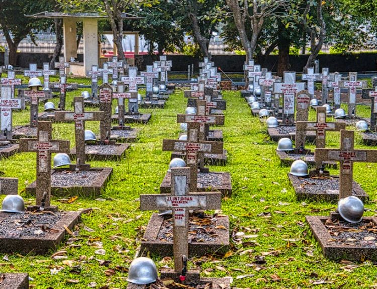 A serene view of a military cemetery in Jakarta featuring cross headstones and lush greenery.