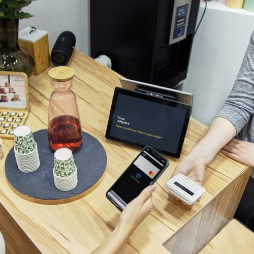 A woman makes a contactless payment at a stylish Berlin café, emphasizing technology and modern retail.