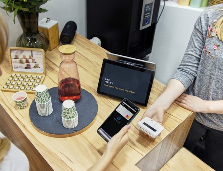 A woman makes a contactless payment at a stylish Berlin café, emphasizing technology and modern retail.