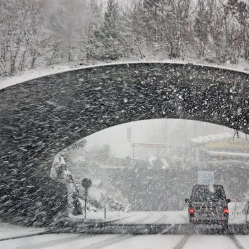 A winter storm covers a Swiss bridge in snow, creating a beautiful yet hazardous landscape.