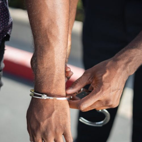 Close-up of a police officer handcuffing a suspect outdoors, enforcing law.