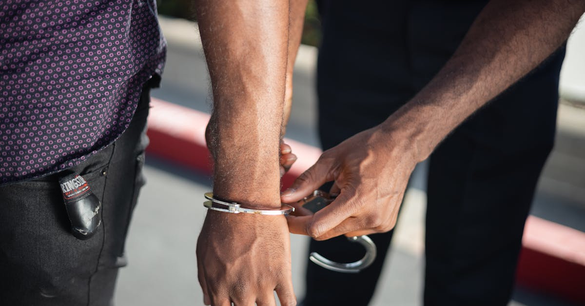 Close-up of a police officer handcuffing a suspect outdoors, enforcing law.
