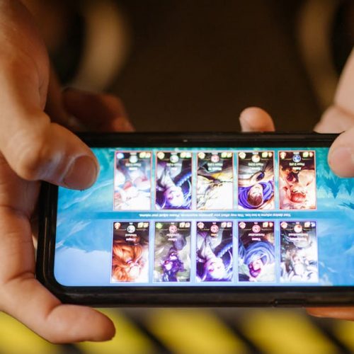 Close-up of hands playing a mobile game on a smartphone, showcasing the game's interface.