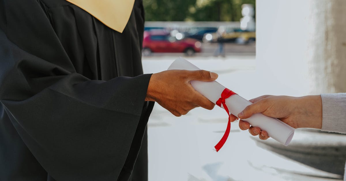 Close-up of a graduate receiving a diploma outdoors in cap and gown.
