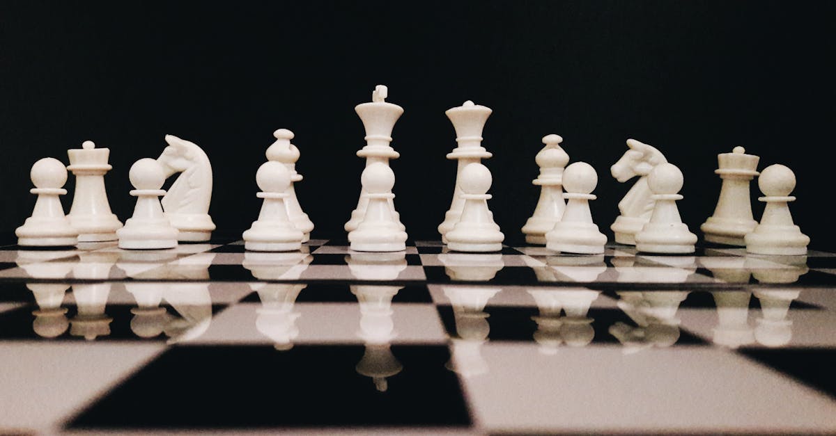 White chess pieces strategically placed on a board reflecting against a black background.