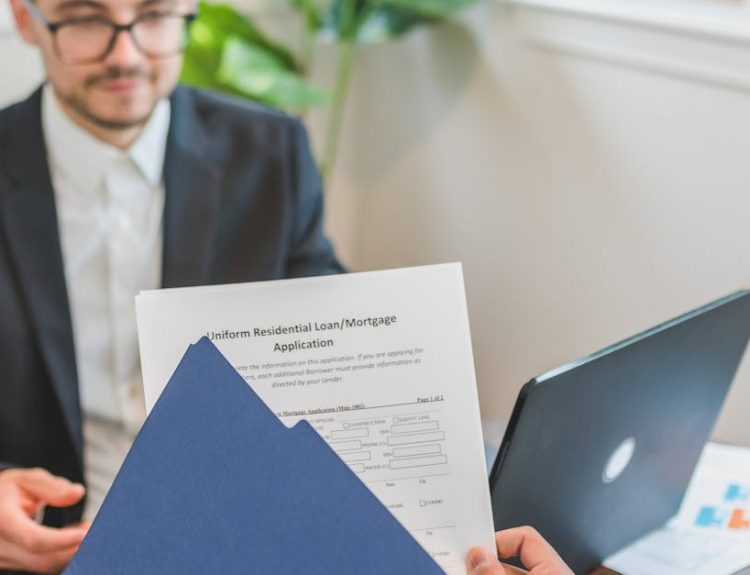 Mortgage broker and client discussing loan application with documents on table.