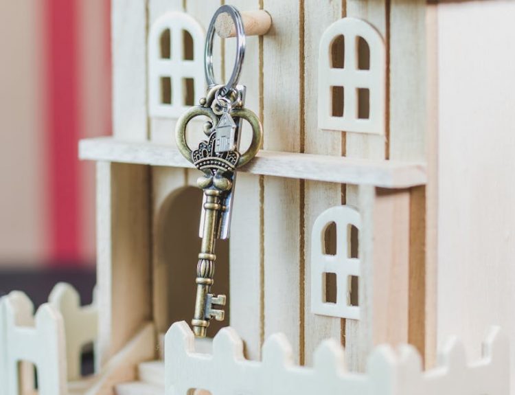 Miniature wooden house with a vintage key, symbolizing real estate and homeownership.