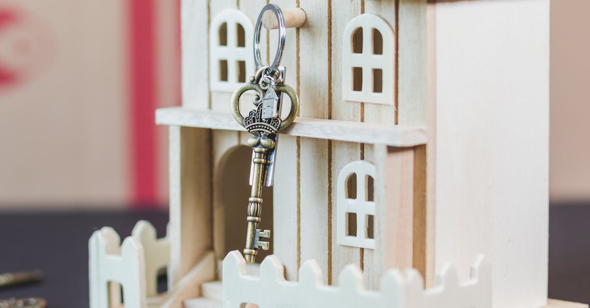 Miniature wooden house with a vintage key, symbolizing real estate and homeownership.