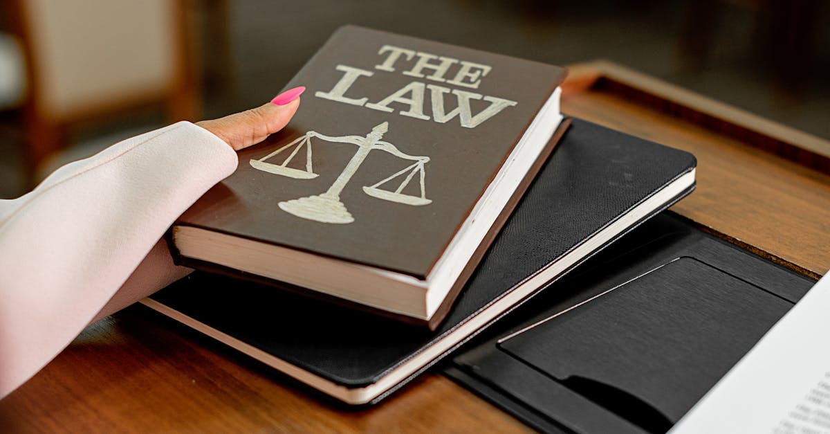 Closeup image of a law book titled 'The Law' on a wooden desk with scales of justice.