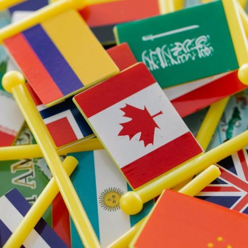 Colorful mini flags of countries on a world map, symbolizing global connections.