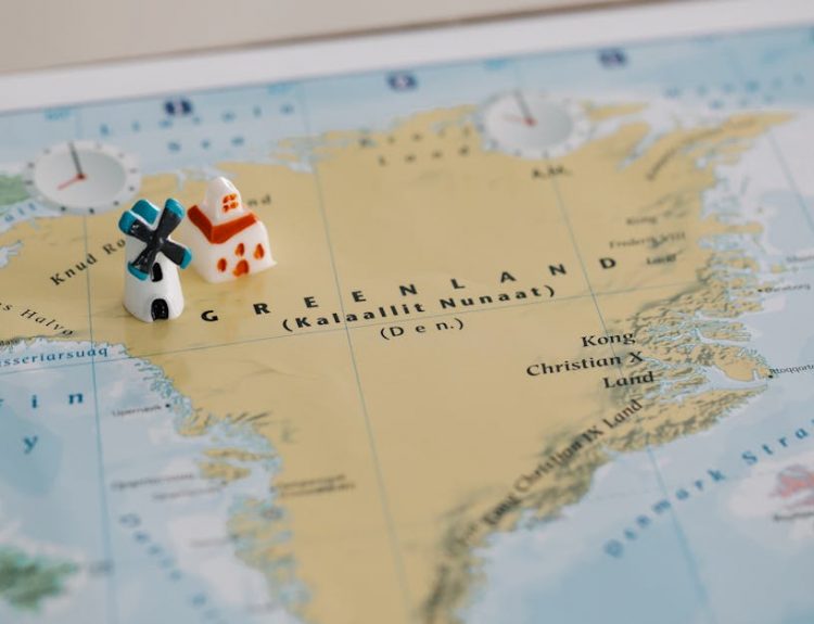 Toy houses on a detailed map of Greenland, highlighting geographic features. Ideal for travel concepts.