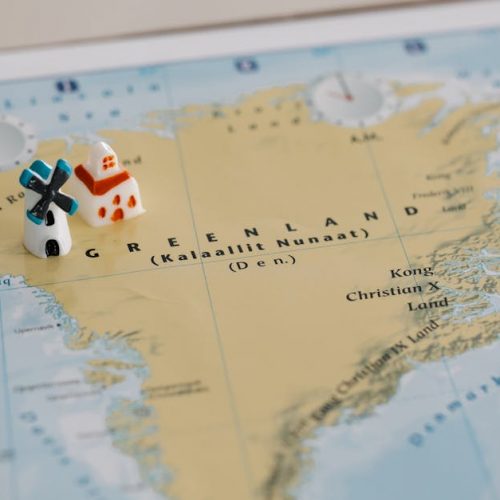 Toy houses on a detailed map of Greenland, highlighting geographic features. Ideal for travel concepts.
