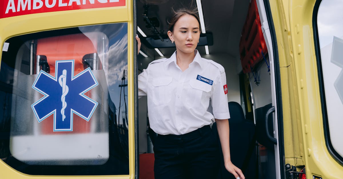 A female paramedic in uniform steps out of a yellow ambulance, ready for action.