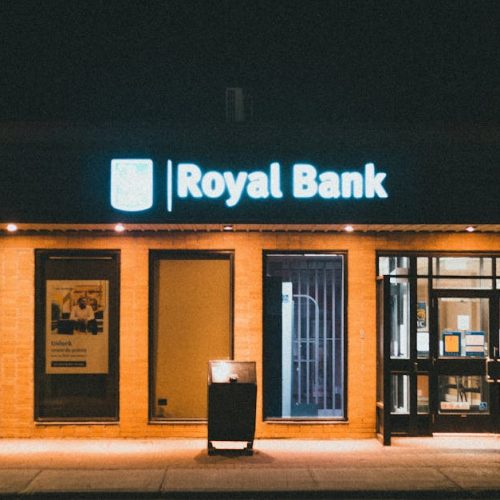 Exterior view of a Royal Bank building at night with glowing facade lights.