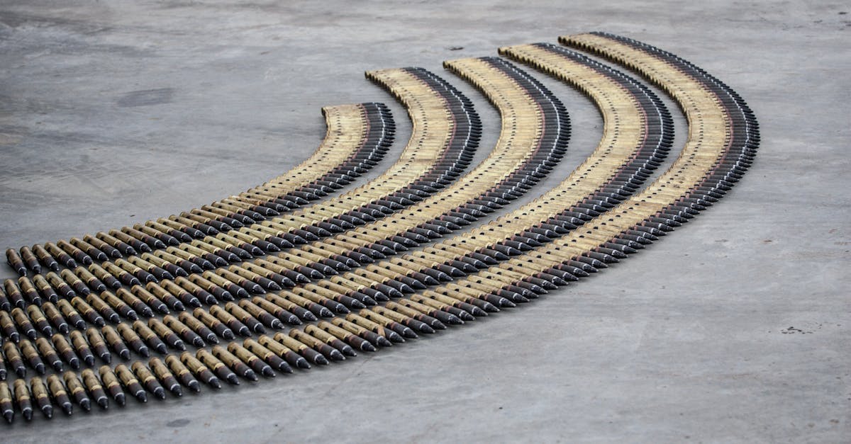 Curved rows of bullets aligned meticulously on a concrete floor, creating a pattern.