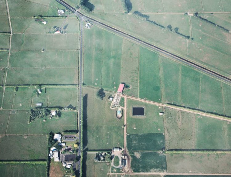 Aerial shot showcasing expansive green farmland with field boundaries and rural structures.