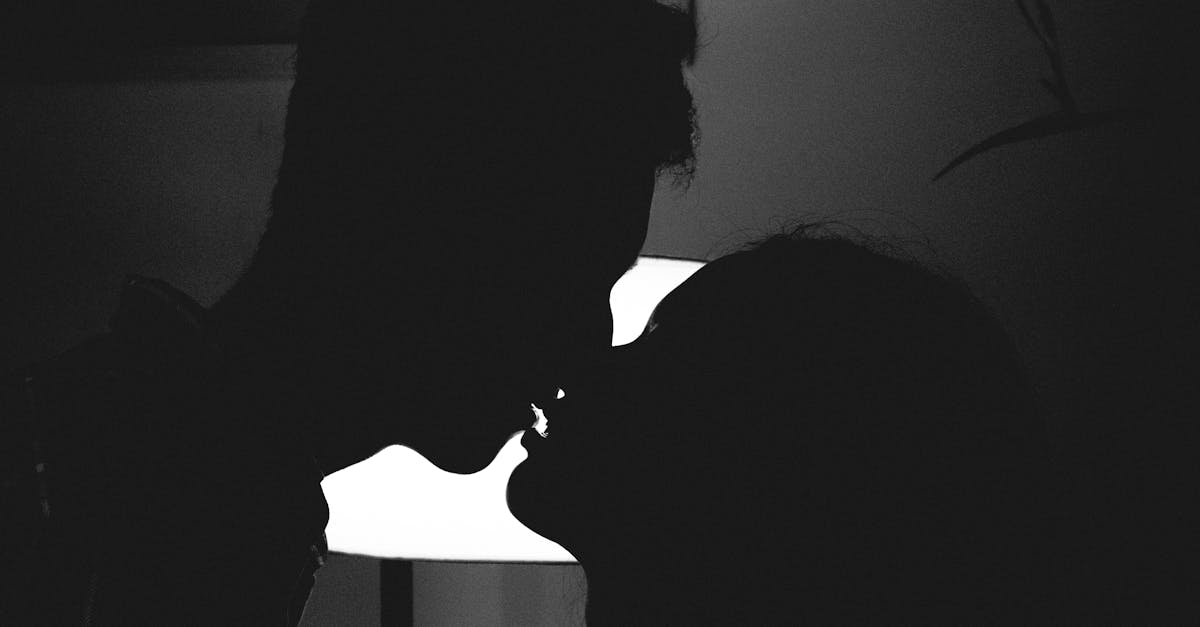 Silhouette of a couple kissing in a romantic and intimate moment against a bright light.