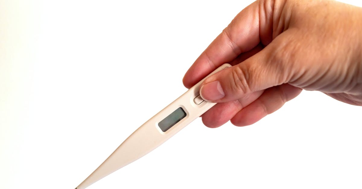 Close-up of a hand holding a digital thermometer, ideal for health and medical concepts.