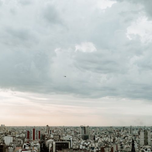 A panoramic aerial view of Buenos Aires skyline under a cloudy sky, emphasizing urban density.